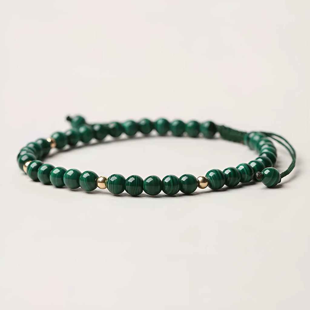 Natural green malachite crystal bracelet with golden balls on a woven hand strap.