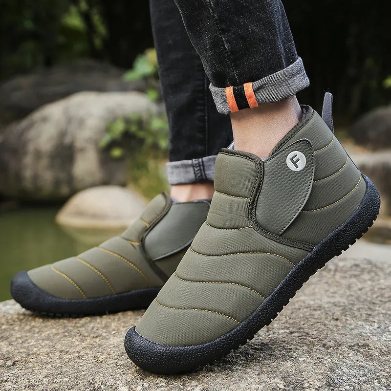 Men's thick black waterproof snow boots with a rubber sole on a hard surface.