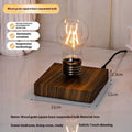 Small black suspension bulb night lamp with an iron art base on a wooden desk.