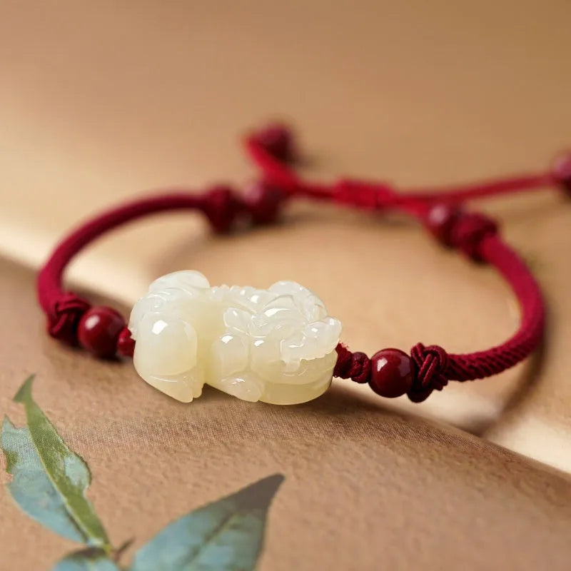 Close-up of a brown and black braided rope bracelet with a central Hetian jade bead on a wrist.