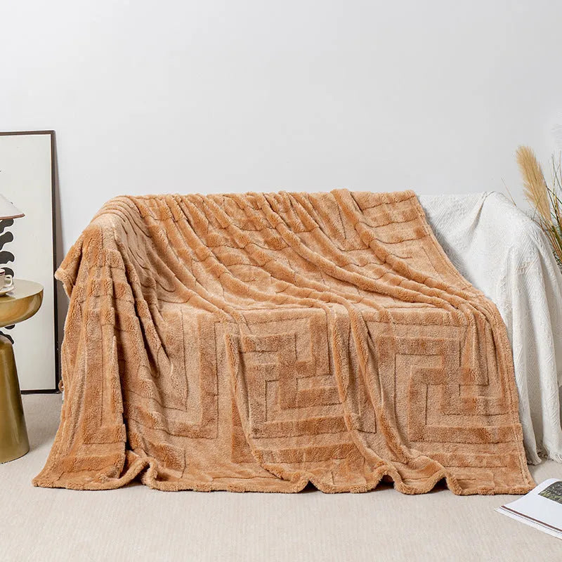 Thick square coral fleece flannel blanket in a solid colour, folded on a sofa.