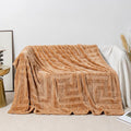 Thick square coral fleece flannel blanket in a solid colour, folded on a sofa.