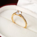 Geometric hexagonal copper ring with a zircon stone, shown in a gold rose red electroplated finish on a size 7 finger.