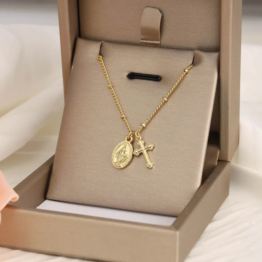 Geometric gold Virgin Mary and cross pendant necklace on a chain, showing minimalist design.