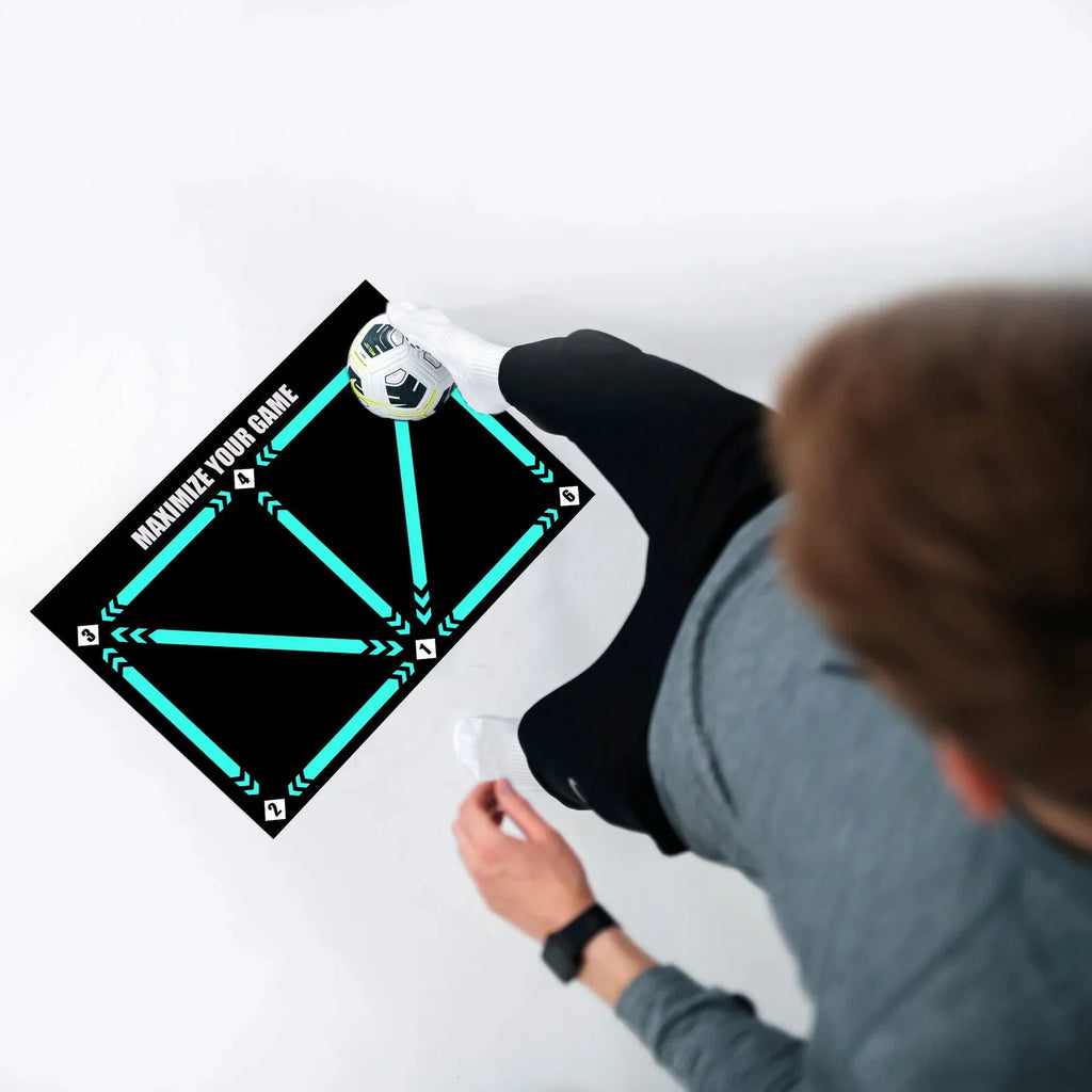 Black rubber football training mat measuring 60cm by 90cm on grass surface
