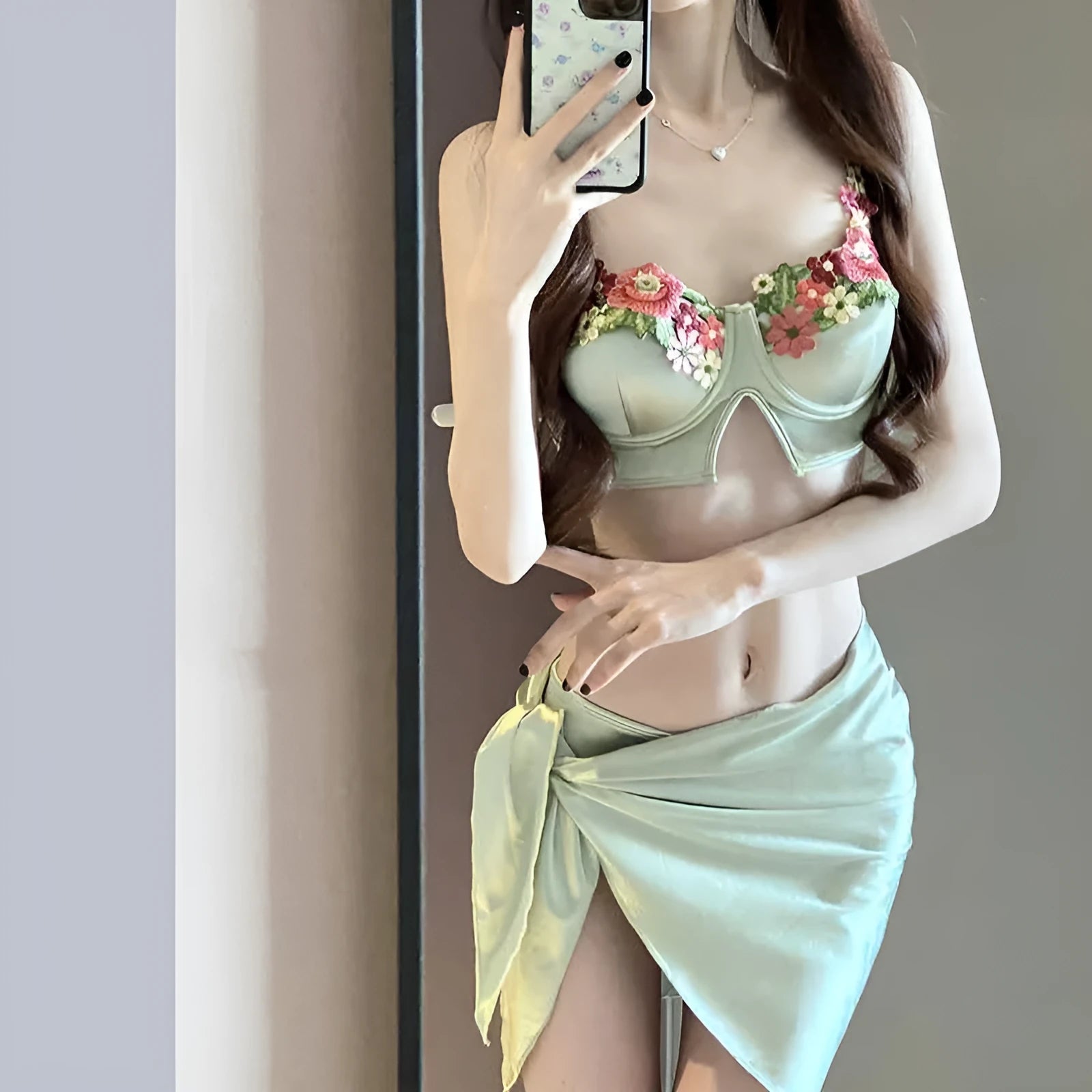 Green women's three-piece bikini set showing sleeveless triangle top, briefs, and a skirt on a mannequin.
