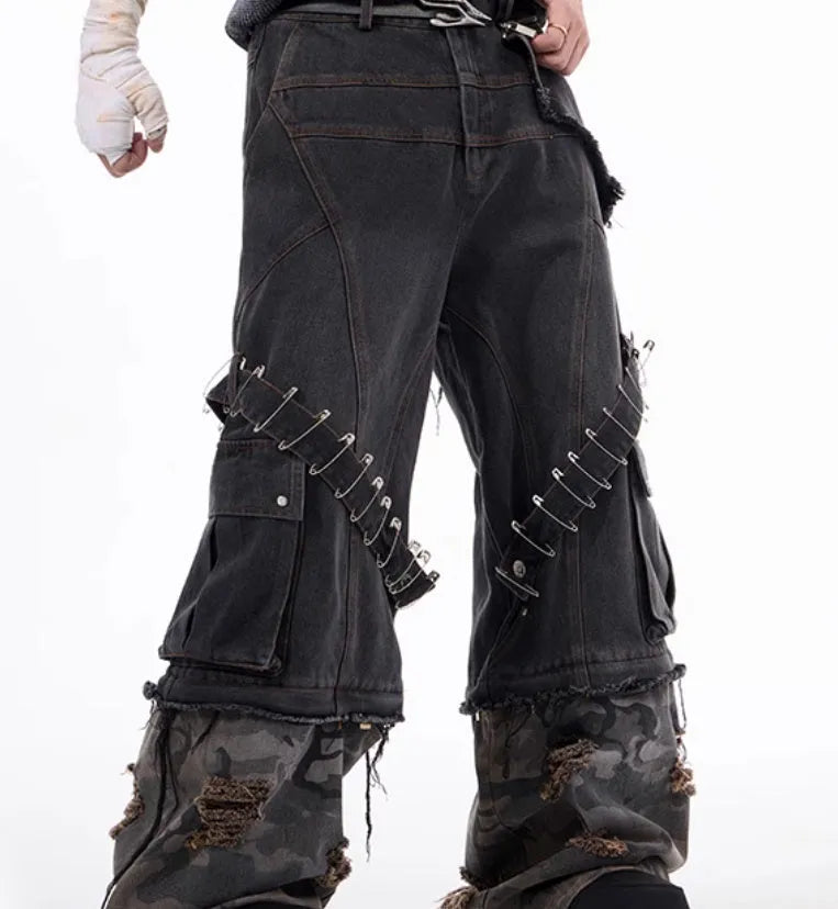 Men's grey jeans with camouflage splicing design and pin and ribbon details on the legs.