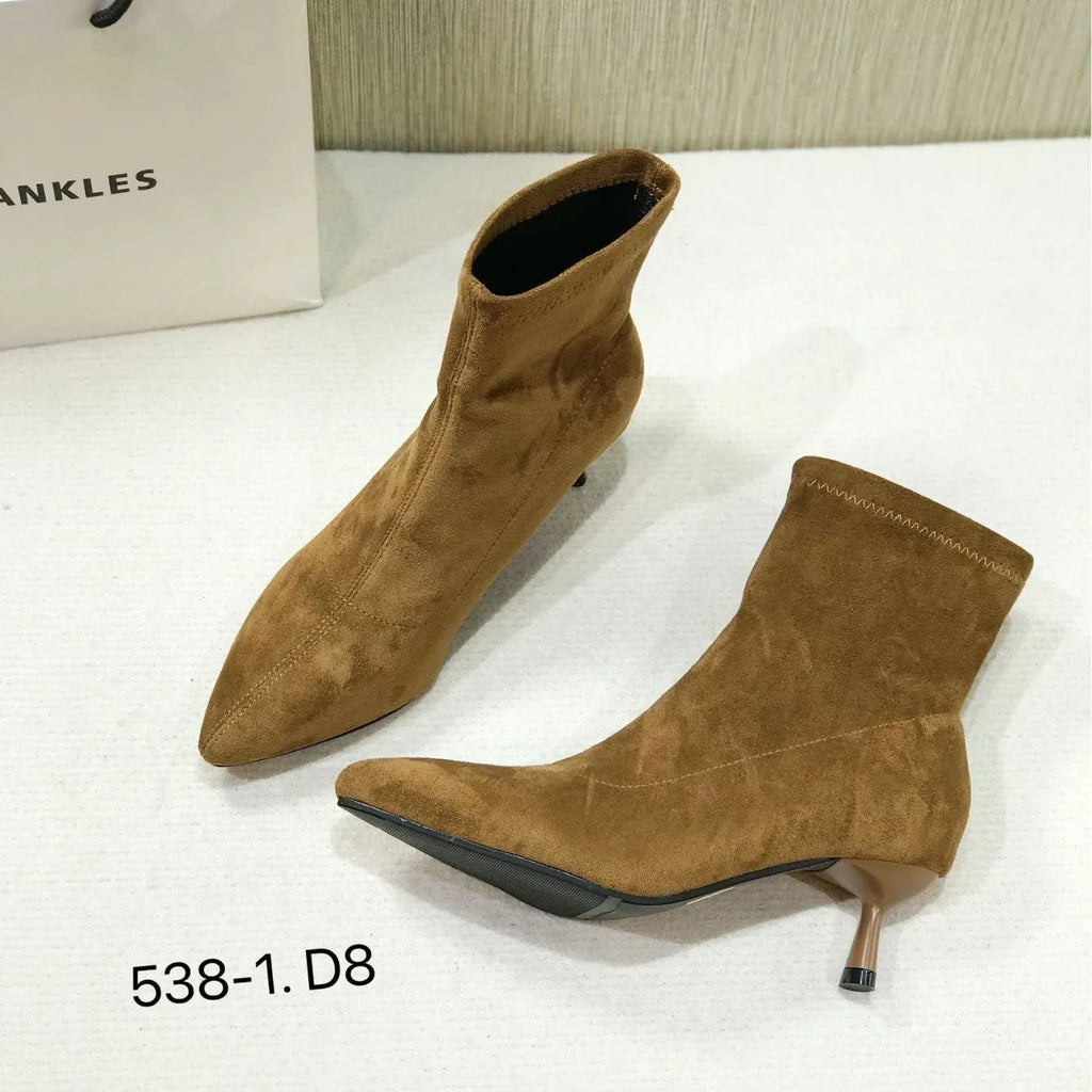 Black women's pointed toe ankle boots with a stiletto heel, shown on a foot.