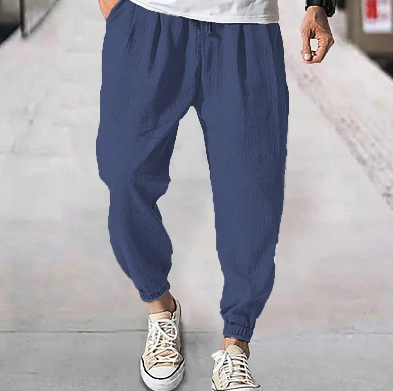 Men's loose-fit light green cotton casual trousers with a banded ankle cuff on a plain background.