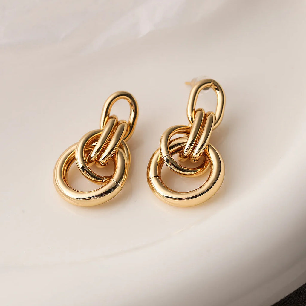 Gold geometric drop earrings with irregular design elements on copper base
