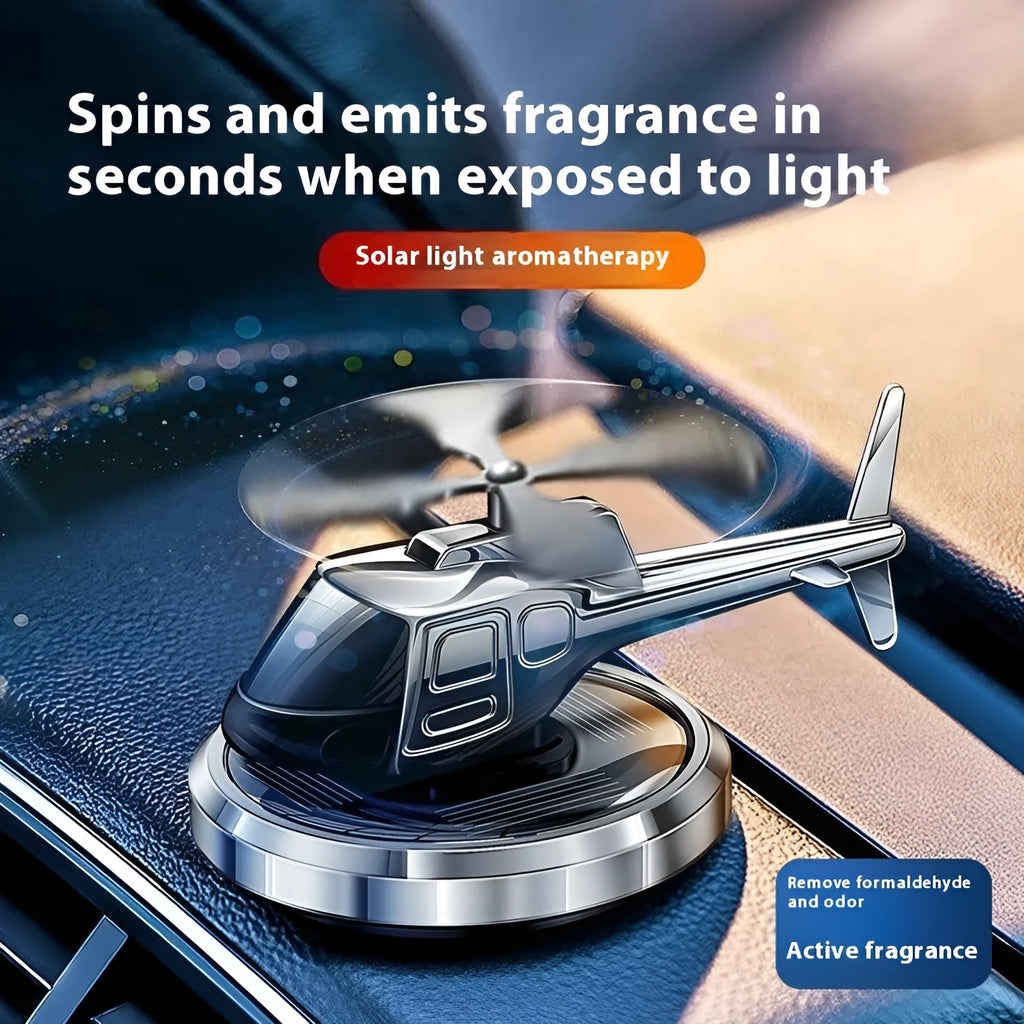 Silver metal solar-powered helicopter car air freshener rotating on a dashboard