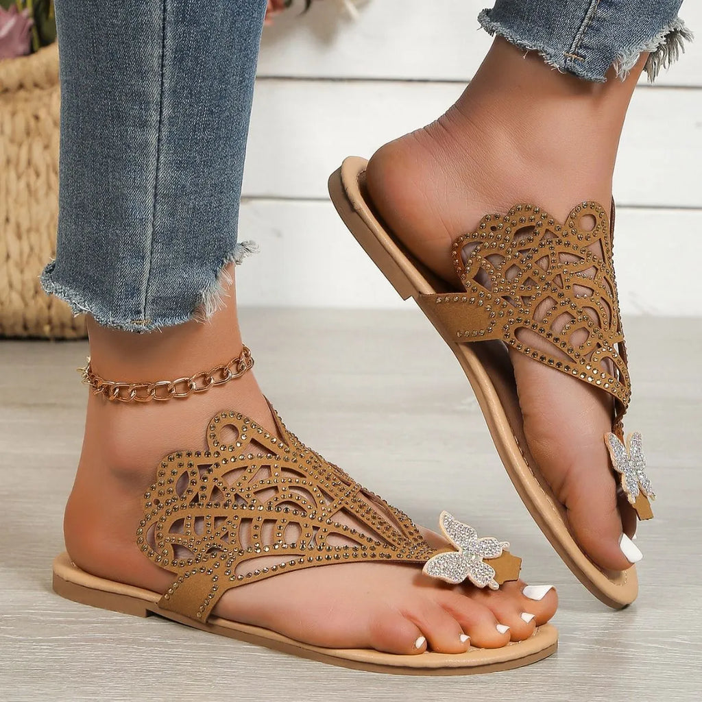 Women's black slip-on sandals with rhinestone decoration and an open flip-toe design on a flat rubber sole.
