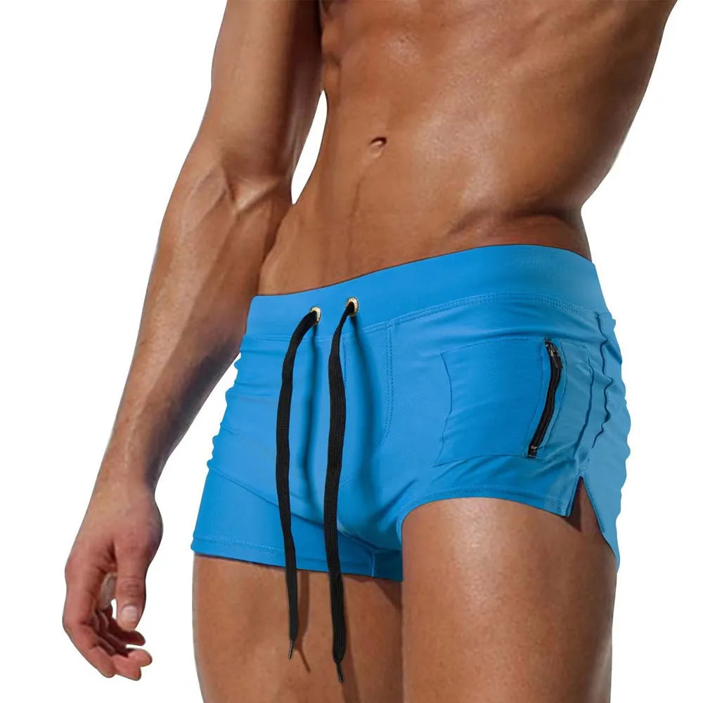 Men's solid colour polyester swimming trunks with high waist and lace-up brief design.