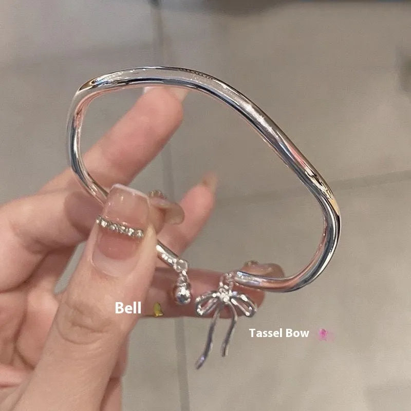 Silver adjustable bracelet with a detailed opening bow charm on a model's wrist, showing the lobster clasp.