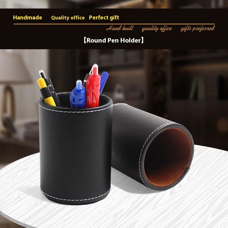 A small, round black leather pen holder standing on a wooden desk.