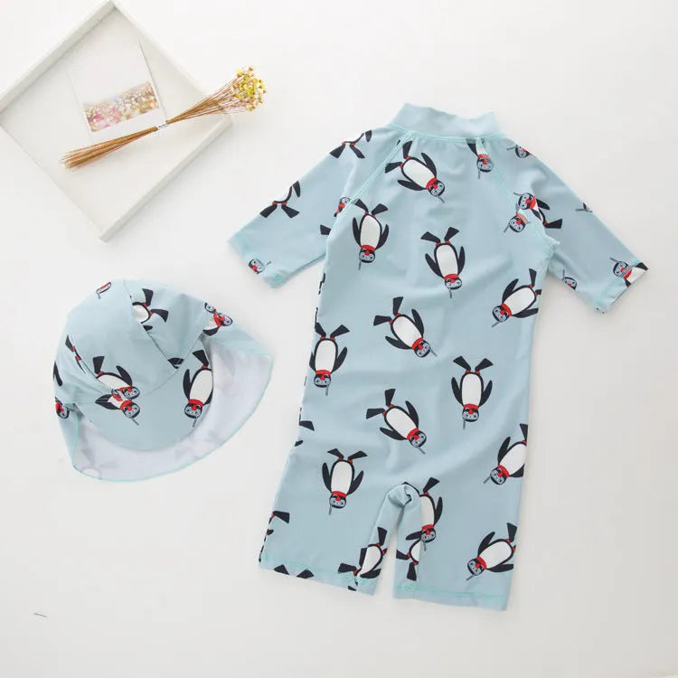 Boy in penguin print long sleeve one-piece swimsuit and matching swimming cap