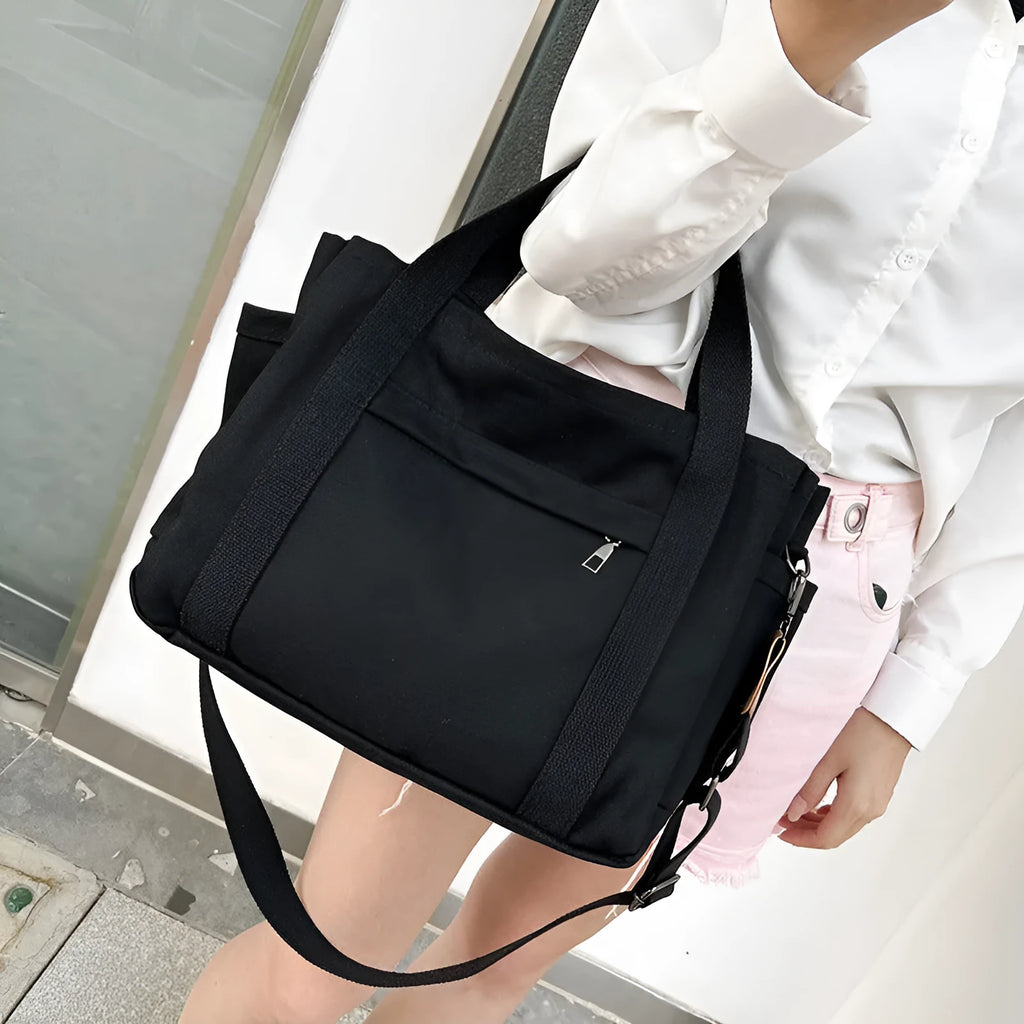 A horizontal square canvas tote bag in army green with a cross-body strap and visible sewing lines.