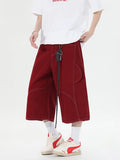 Red and black denim workwear shorts with multiple pockets, cropped length, and wide leg design