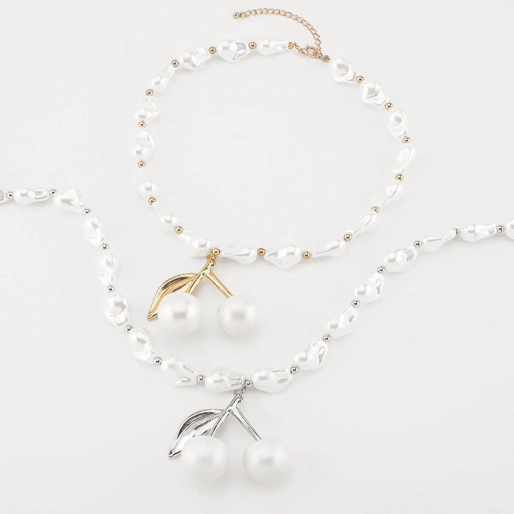 Gold-tone irregular cherry fruit pendant on an adjustable string of white imitation pearls necklace.