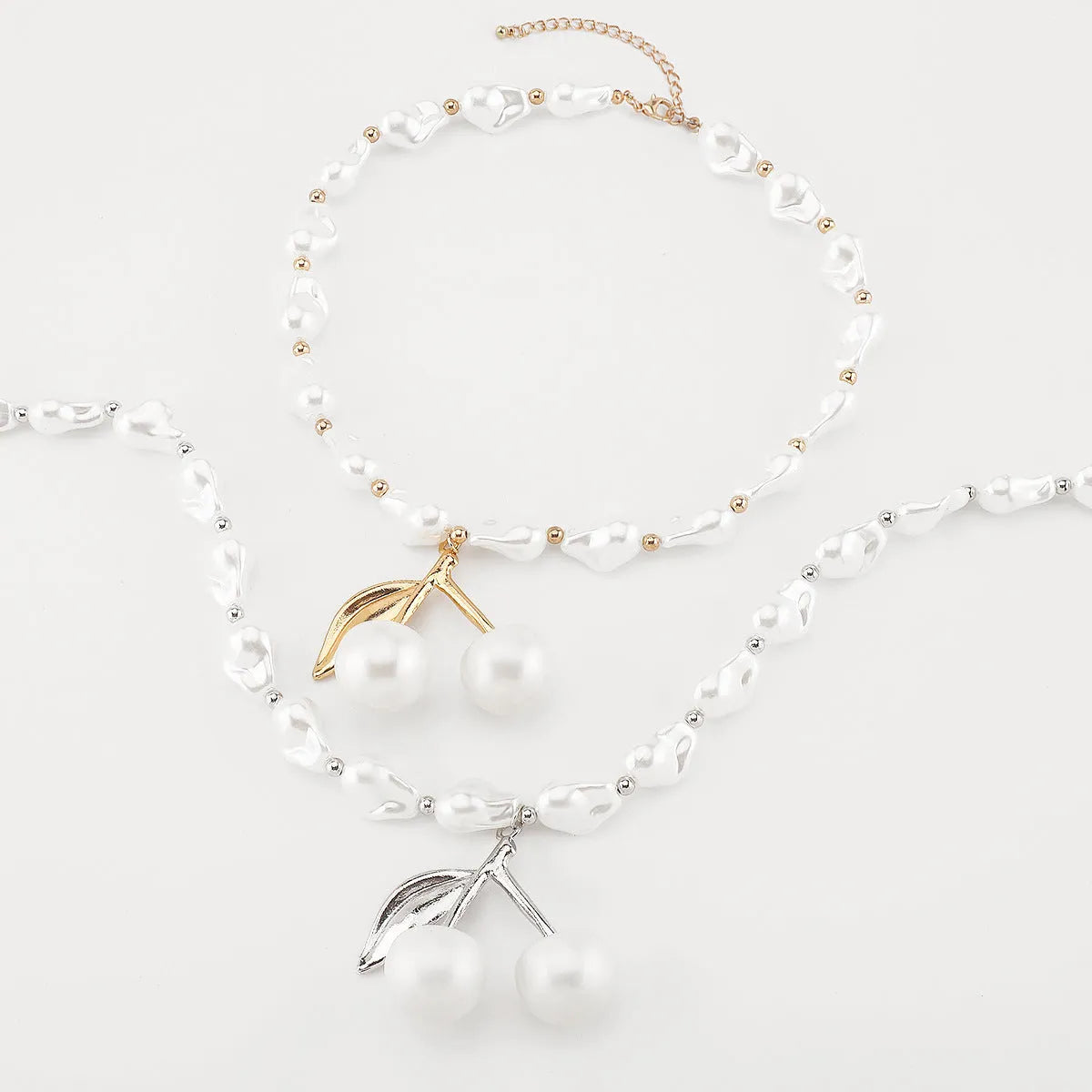 Gold-tone irregular cherry fruit pendant on an adjustable string of white imitation pearls necklace.