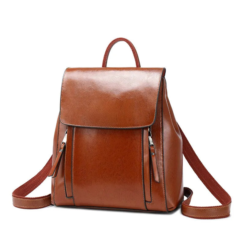 Brown oil-waxed cowhide leather women's backpack with flap closure, showing internal document pocket and stitching detail.