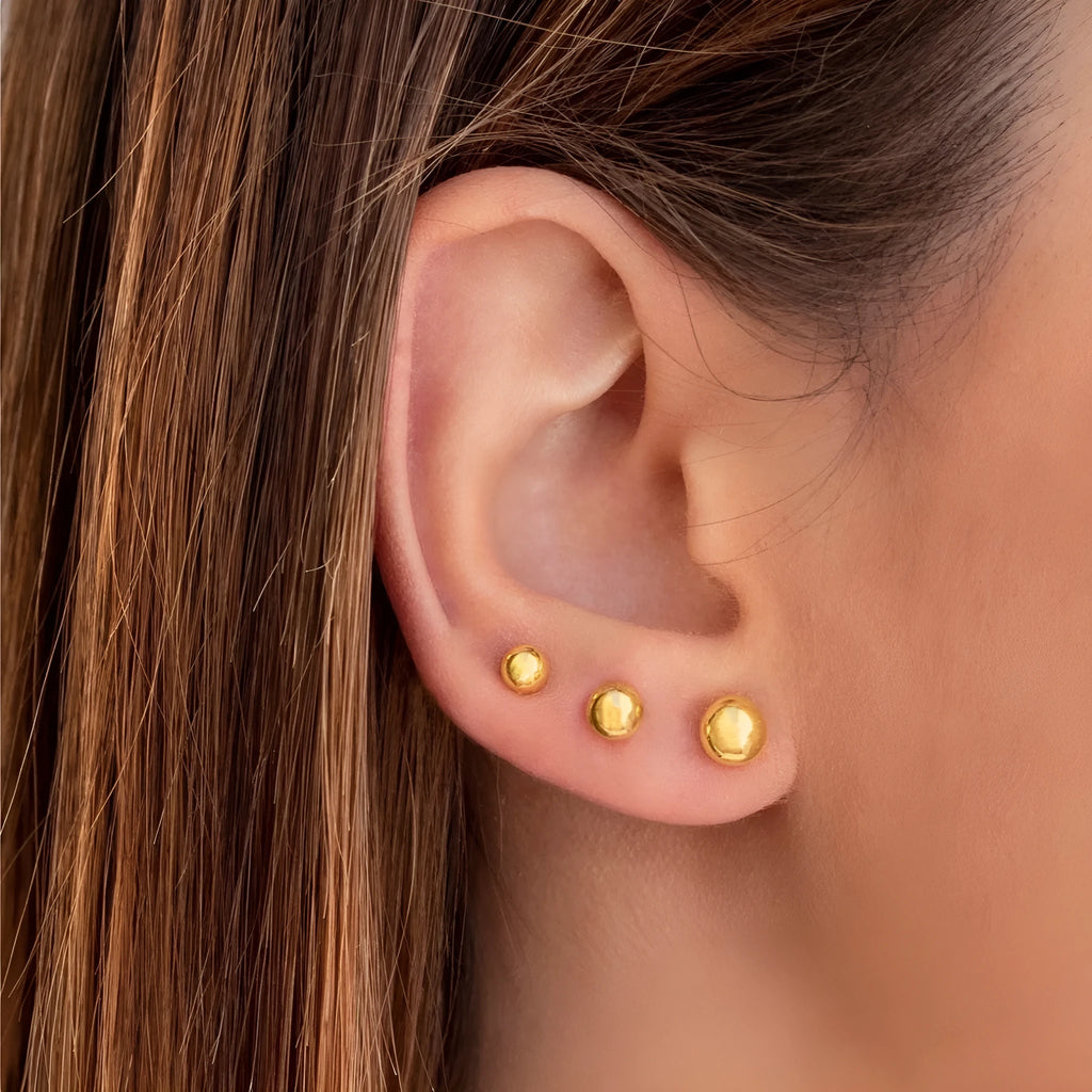Simple gold-coloured stainless steel ball stud earrings in geometric design on a white background.