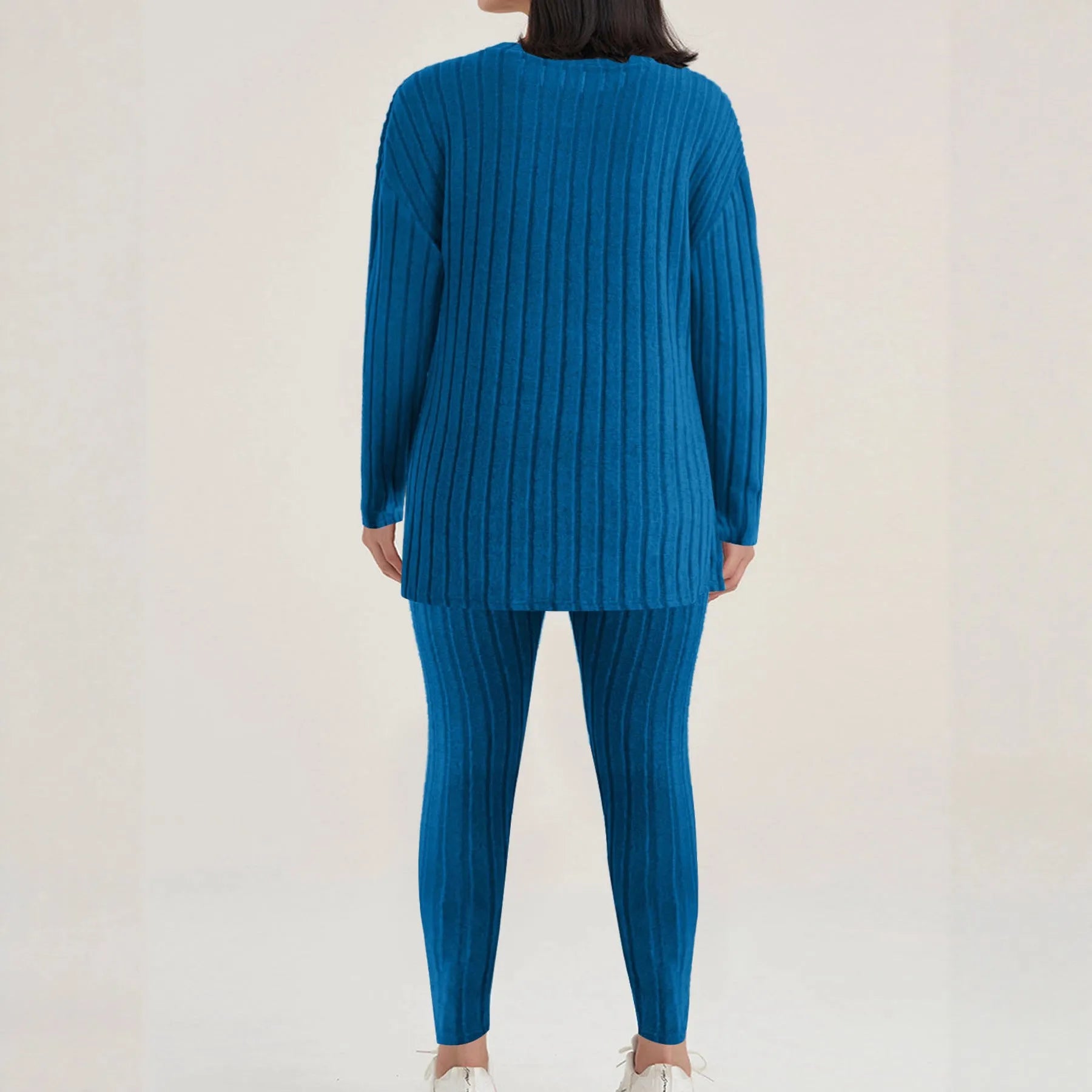 A woman wearing a black sunken stripe two-piece loungewear set, consisting of a regular-sleeve top and elasticated waist trousers.