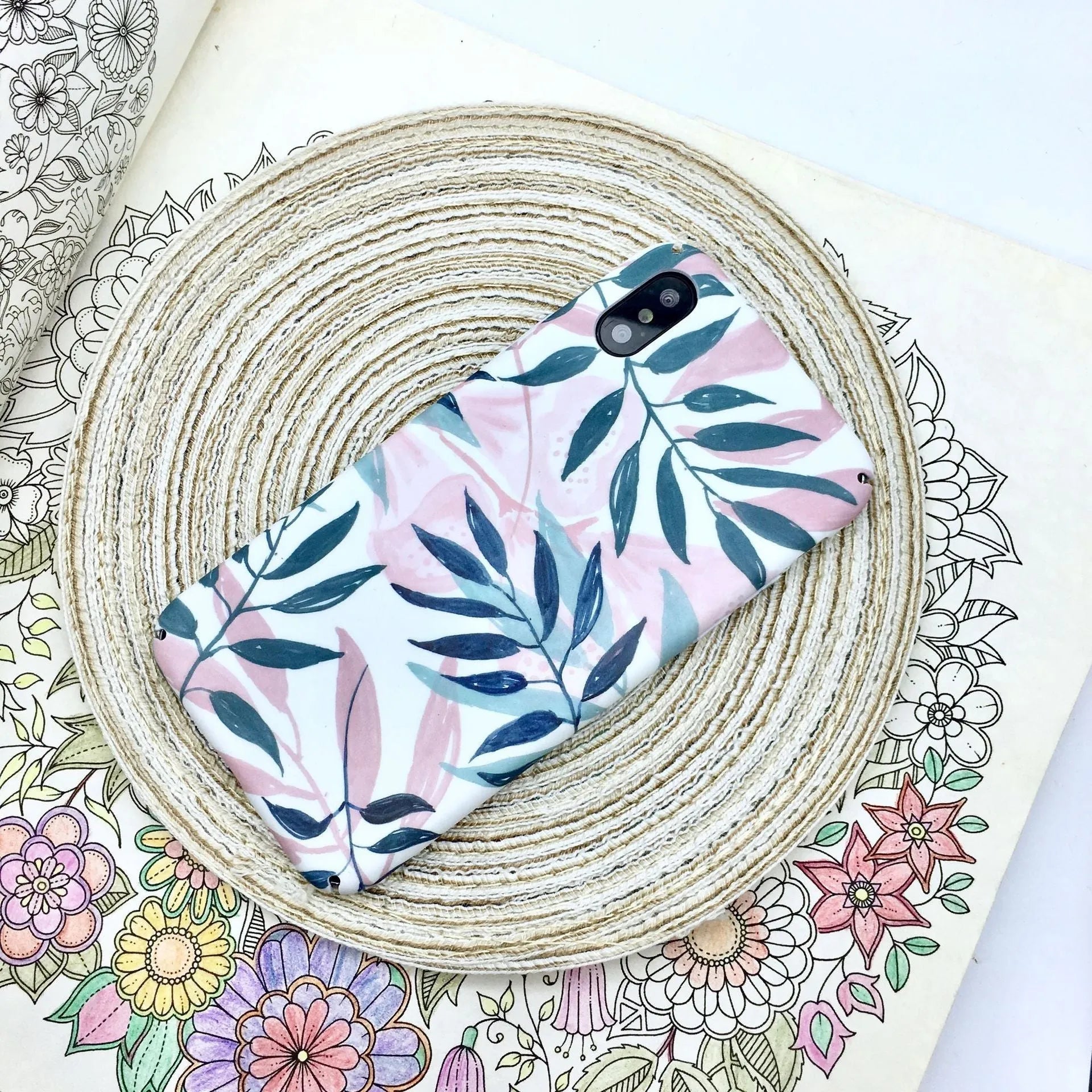 Green and pink painted hard PC back cover cases for smartphones on a table.