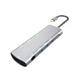Grey aluminium USB-C docking station with HDMI, VGA, USB 3.0, and PD charge ports on a desk.