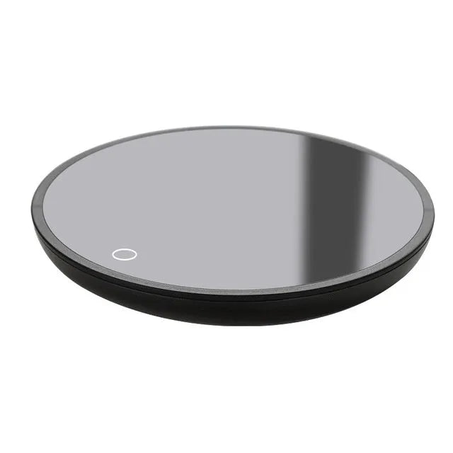 Black round desk cup warmer with tempered glass surface and low high switch on a wooden table.
