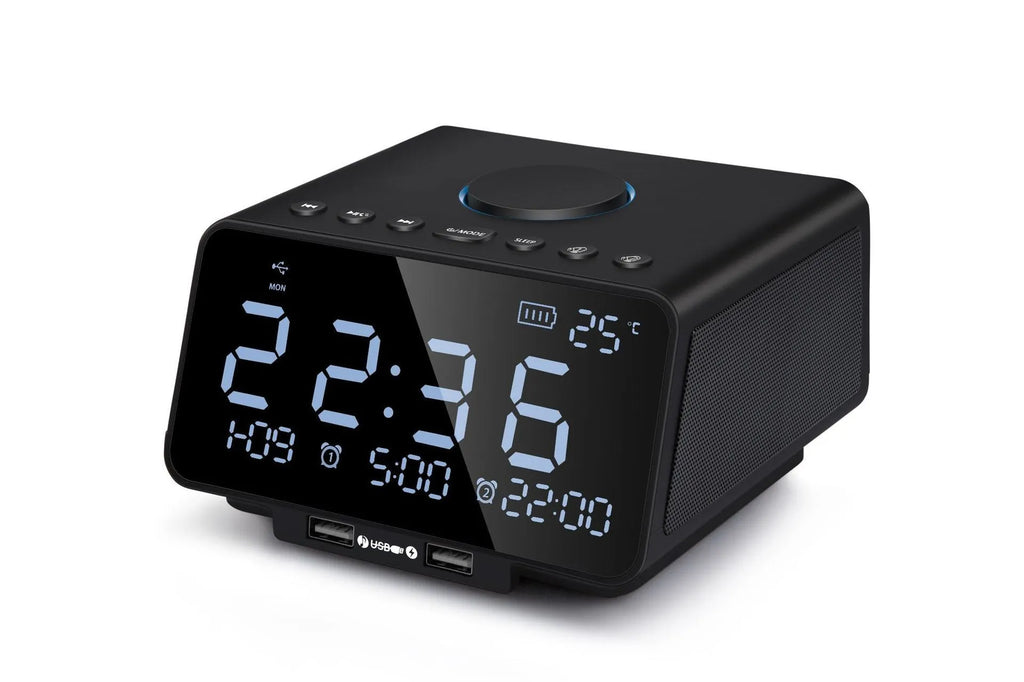 Black and white wireless alarm clock speaker with digital display, twin speakers, and a remote control on a wooden surface.