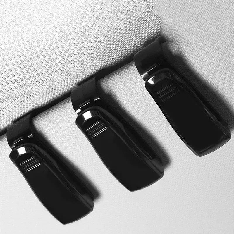 Black plastic multifunctional clip for car sun visors to hold tickets, IDs, or glasses.