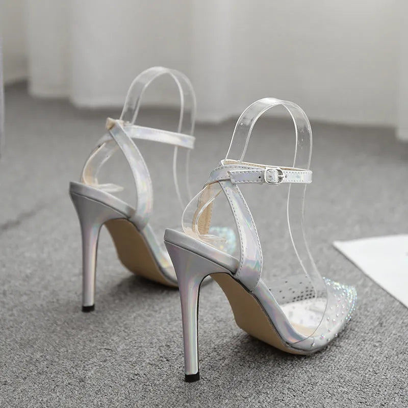 Women's pointed-toe sandals with glossy PVC upper and a thin stiletto heel on a neutral background.