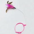 Pink and blue adjustable collar cat teaser toy with feather and bell attachment on a white background