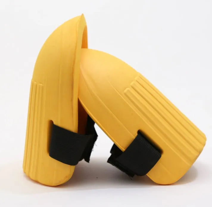 A pair of rectangular EVA foam knee pads in army green colour on a garden soil background.