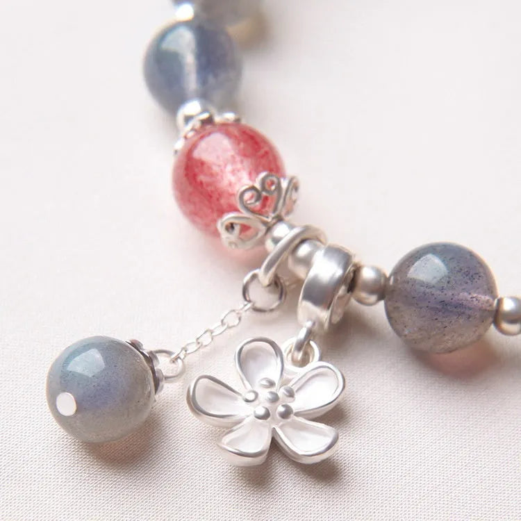 Close-up of a women's 925 sterling silver bracelet with a grey moonstone bead and a zodiac animal charm.