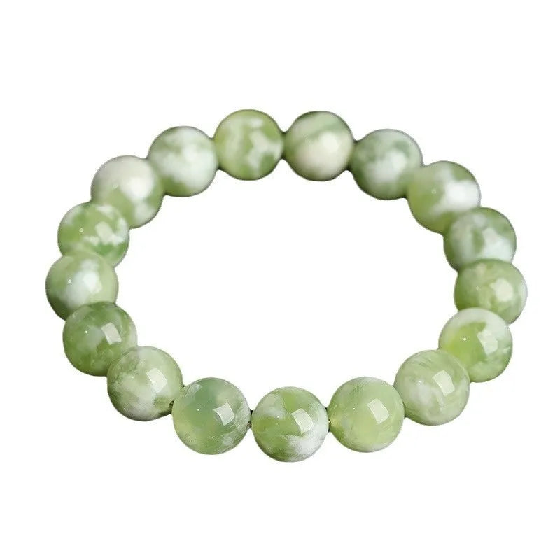 Green milk-in-water Xiuyan jade bracelet with geometric beads on white background