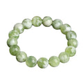 Green milk-in-water Xiuyan jade bracelet with geometric beads on white background