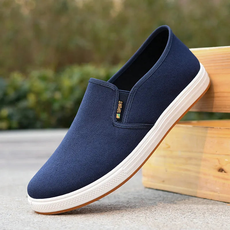 Men's low-top black canvas slip-on shoes with round toe and shallow mouth on a composite sole.
