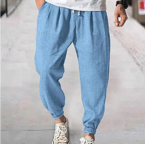 Men's loose-fit light green cotton casual trousers with a banded ankle cuff on a plain background.