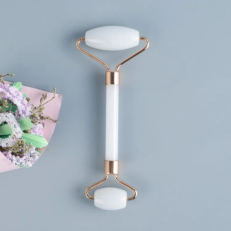 White jade facial roller and Gua Sha scraping board set on a neutral background.