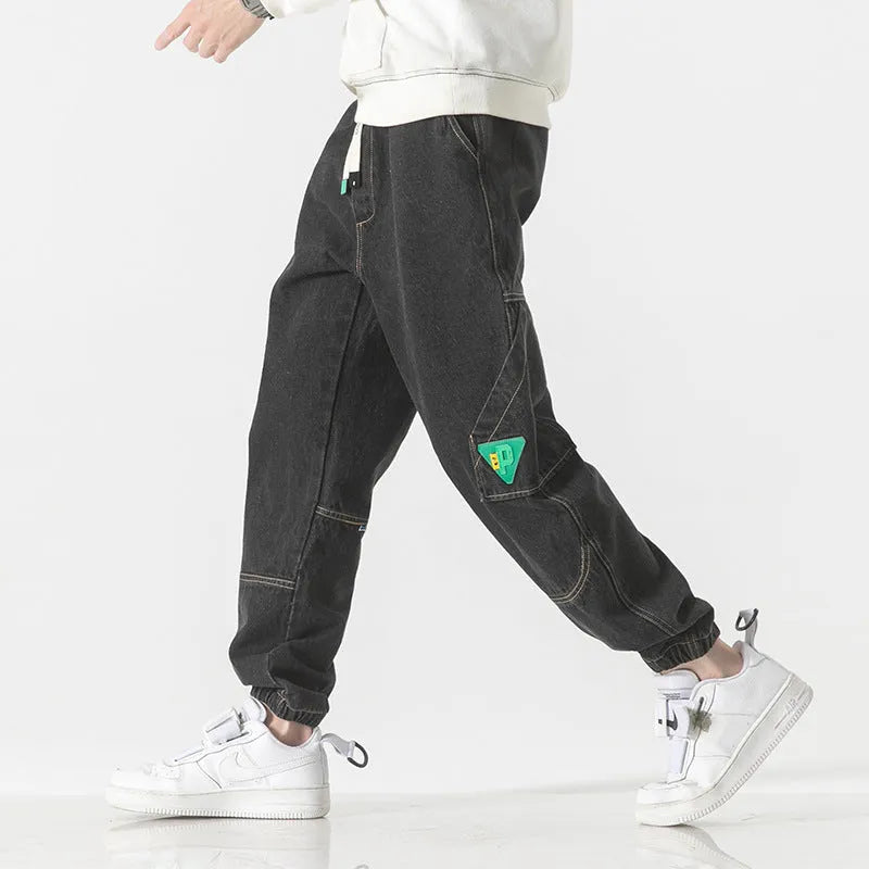 Men's loose-fit tapered cotton trousers in grey colour, shown on a model.