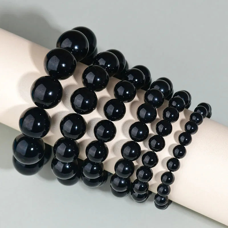 Hand-woven round obsidian bead bracelet on a wrist, showing ethnic style and multiple colour options.