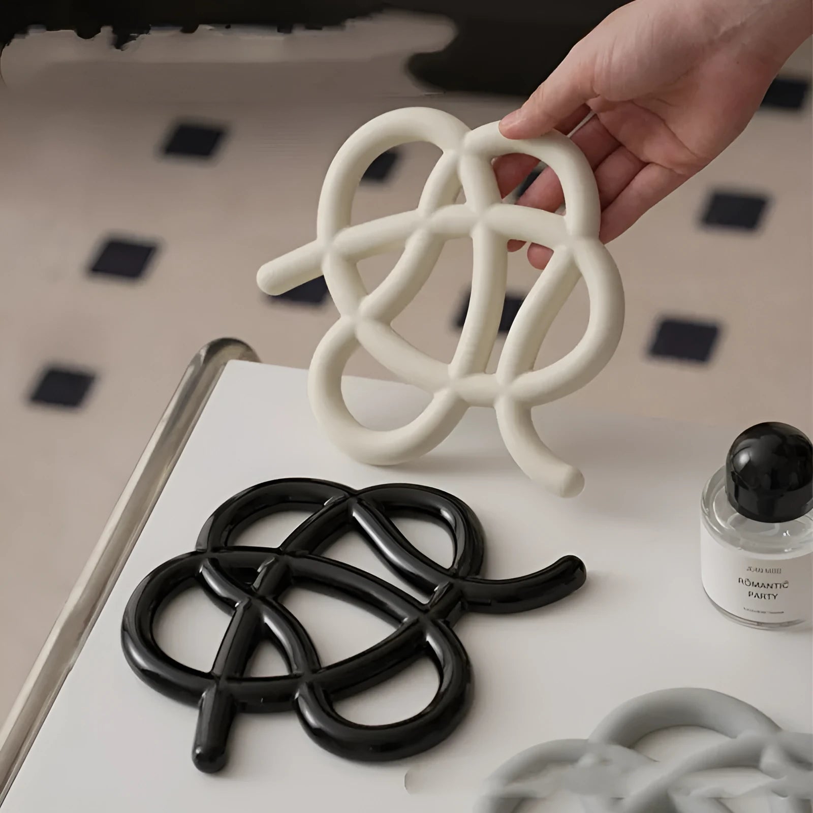 Modern irregular-shaped ceramic heat proof mat in grey on a wooden table protecting it from a hot pan.