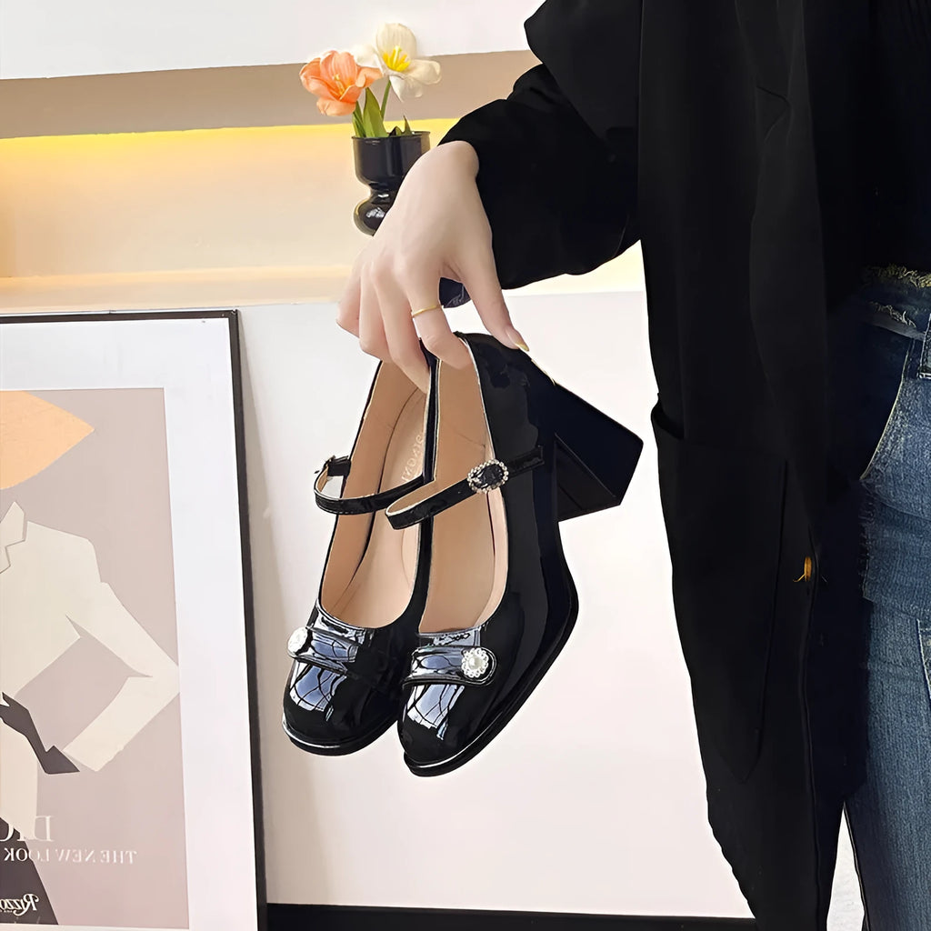 Women's black patent leather wide fit chunky heel shoe with round toe and buckle fastening.