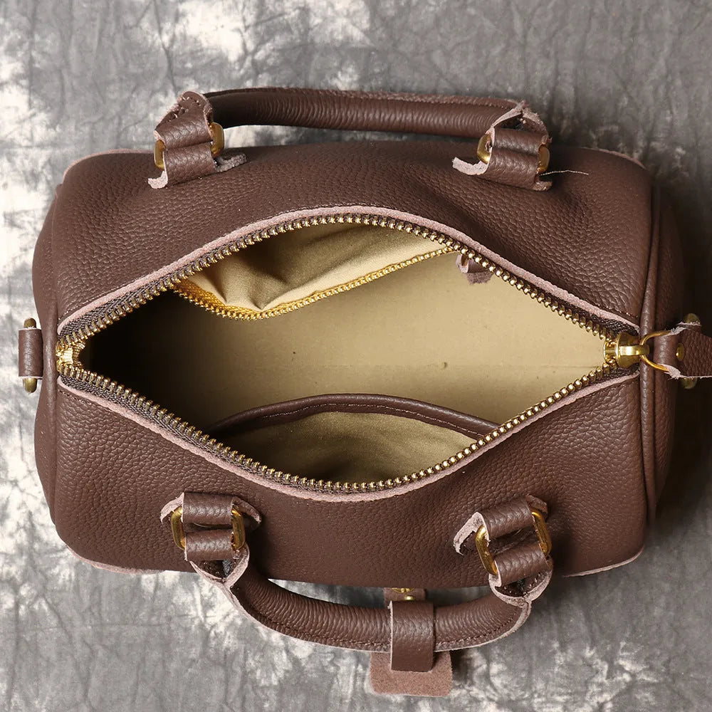Brown yellow cowhide leather Boston bag with single shoulder strap, showing cylindrical shape and open outer pocket.
