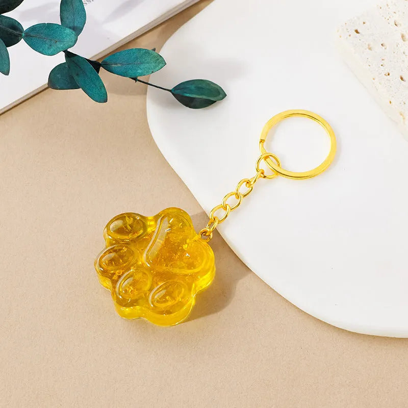 Hand-finished natural crystal cat's paw keychain pendant on a metal ring, showing detailed carving and polished stone surface.