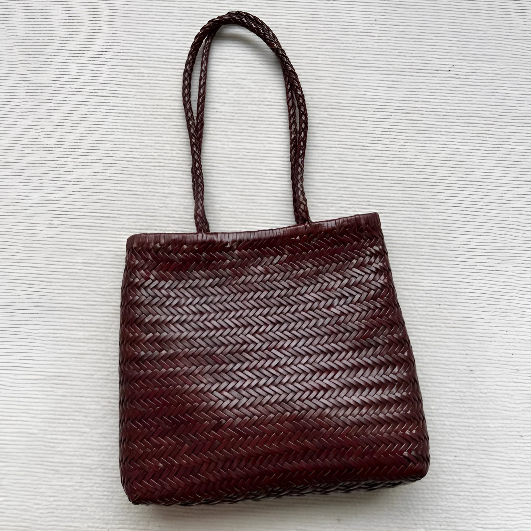 Brown handmade woven leather tote bag with a three-dimensional pocket.