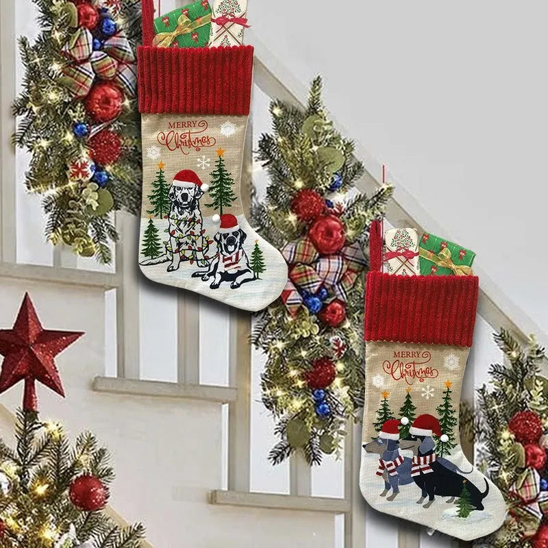 Red and green cloth Christmas stocking pendant for pets, hanging on a tree branch.