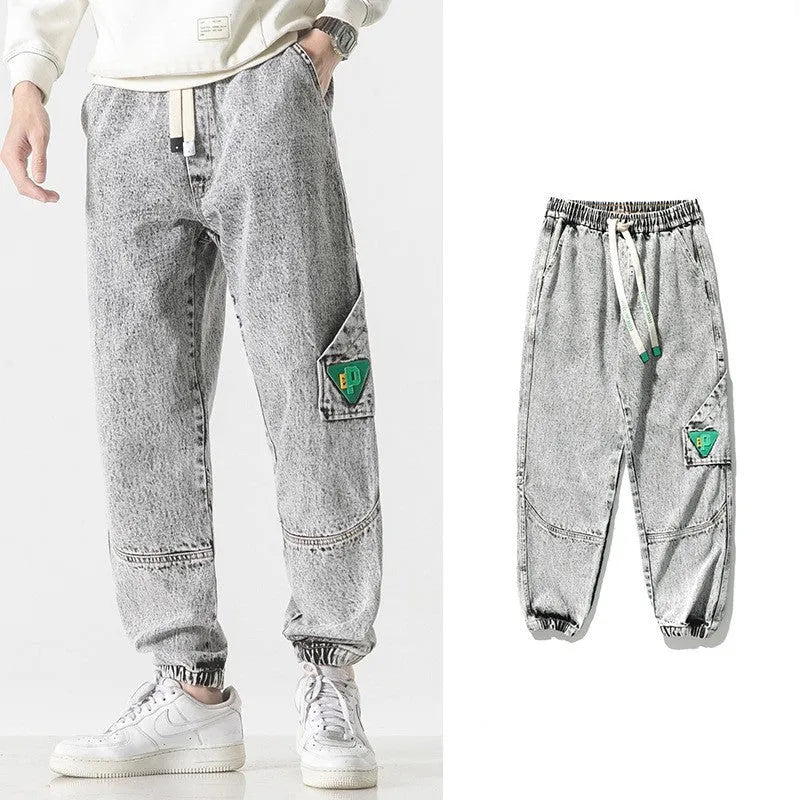 Men's loose-fit tapered cotton trousers in grey colour, shown on a model.
